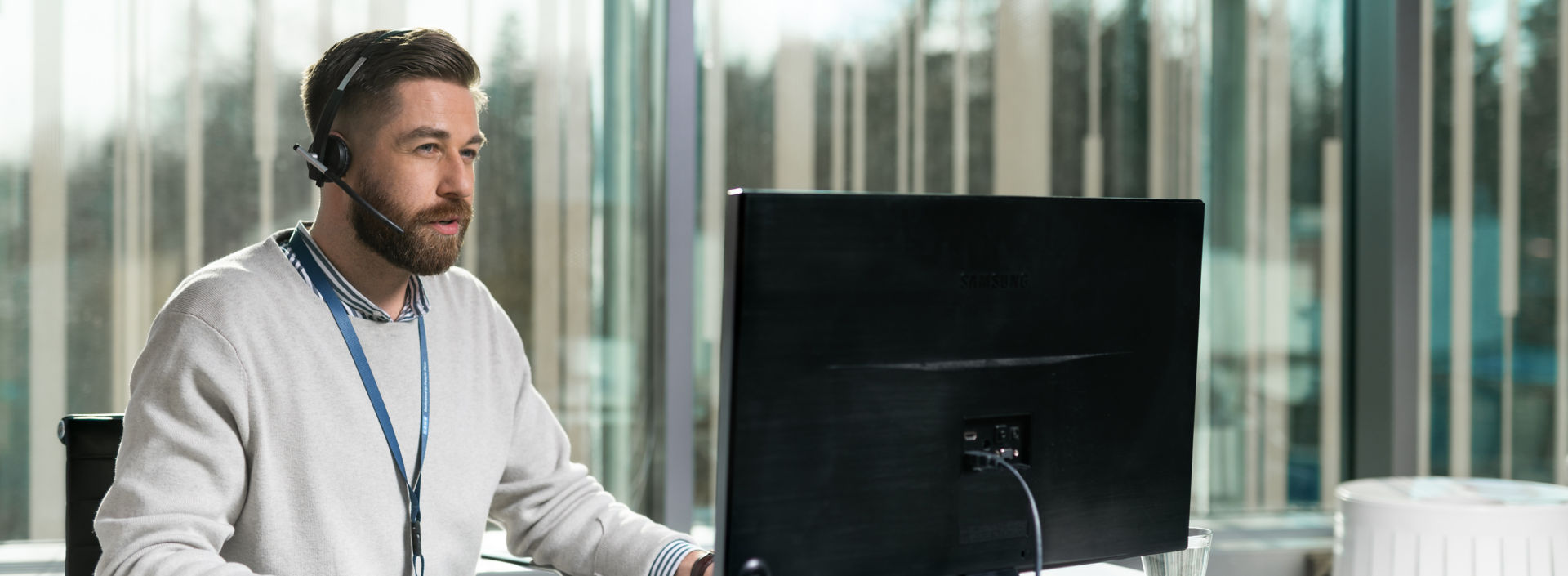 Hombre con auriculares frente a una computadora - KONE Servicio al cliente